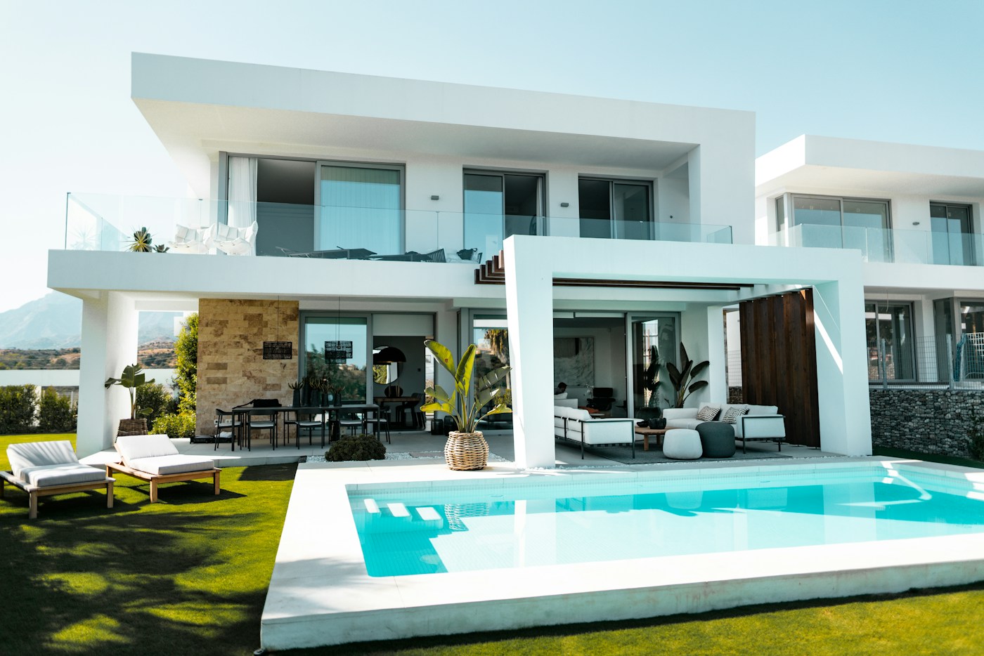 Swimming pool beside a modern villa with a landscaped garden and shaded outdoor seating